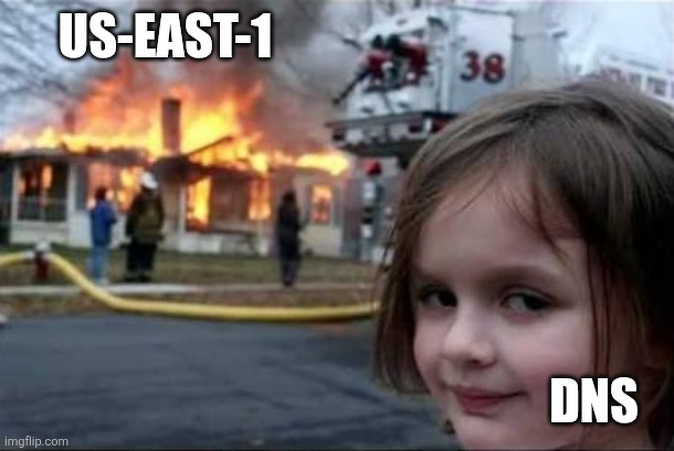 The Disaster Girl meme: a young girl (DNS) smiles in the foreground while a house in the background (US-EAST-1) is engulfed in flames. 